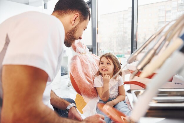 Petite fille visitant un dentiste masculin à la clinique Conception de la stomatologie