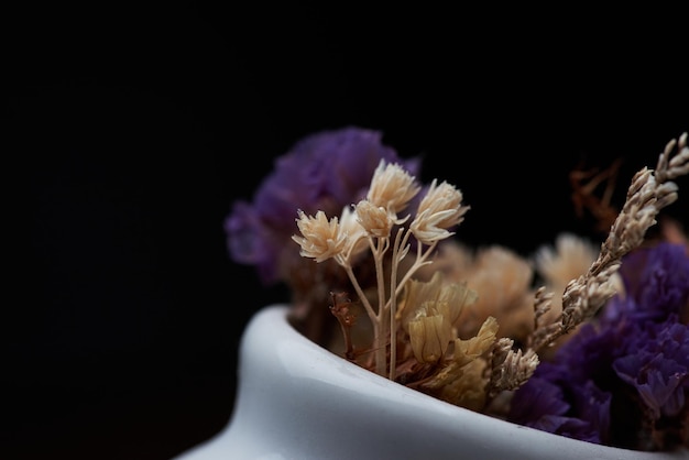 Une petite fleur dans un vase avec des fleurs violettes dessus.