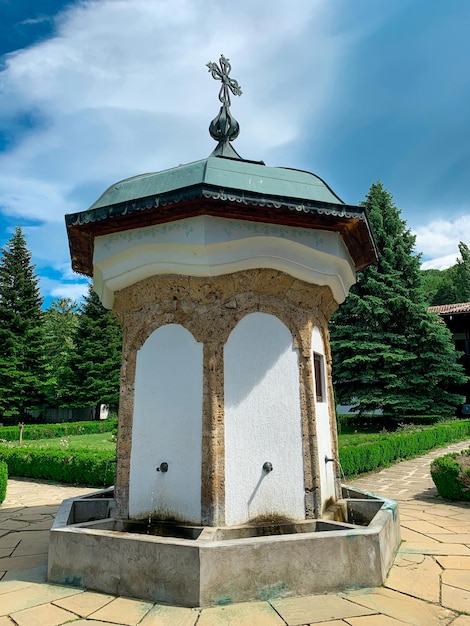 Une petite fontaine d'eau blanche et verte avec un toit vert et un ciel bleu à l'intérieur du monastère de Sokolsky