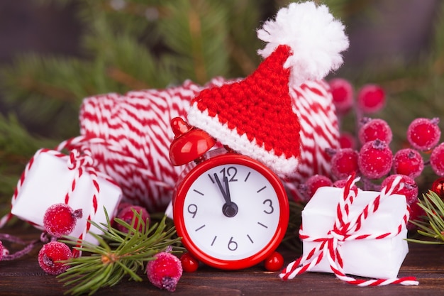 Une petite horloge dans un bonnet de Noël, un cadeau du nouvel an. Décor de noël.