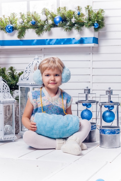 petite jolie fille assise à côté d'un arbre de Noël