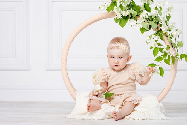 Petite jolie fille aux yeux bleus est assise sur un sol avec des fleurs de jasmin. Copier l'espace