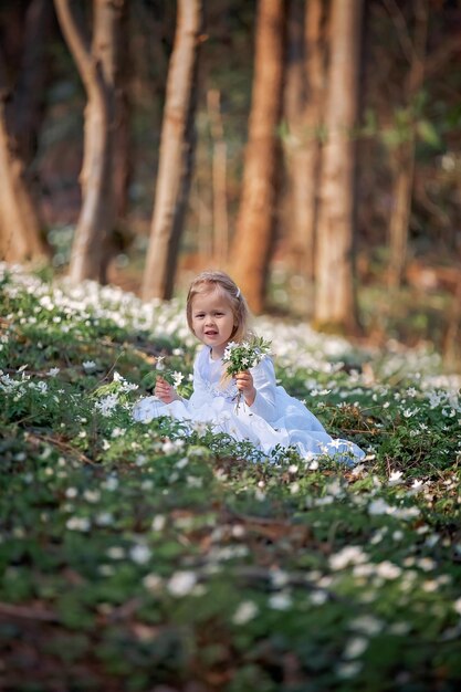 Petite jolie fille dans une clairière de perce-neige Un enfant se promène dans la forêt de printemps