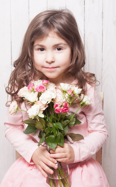 Petite jolie fille en rose tient le bouquet de roses. Fermez les fleurs et le visage