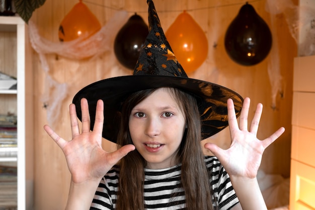 Petite jolie fille sorcière au chapeau de sorcier noir dit Boo avec un geste effrayant Halloween Kids Portrait