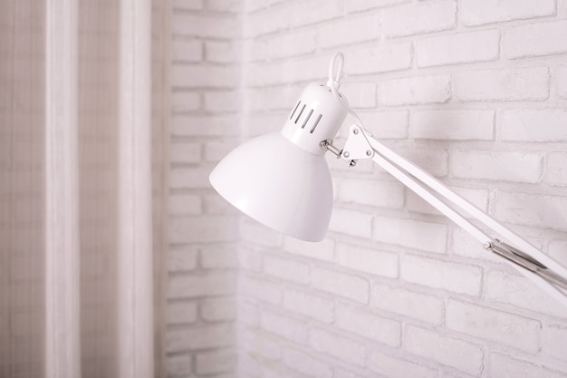 Petite lampe de table sur mur de briques blanches