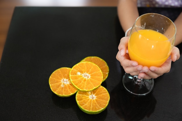 Petite main de fille avec un verre de jus d&#39;orange dans la cuisine