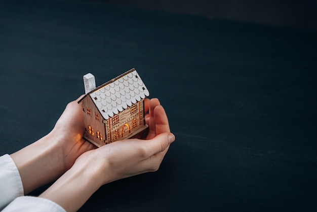 Petite maison aux fenêtres lumineuses entre les mains des femmes