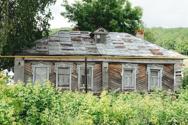 Petite maison en bois abandonnée dans le village parmi la verdure en été