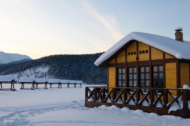 Une petite maison en bois au bord d'un lac gelé sous la neige