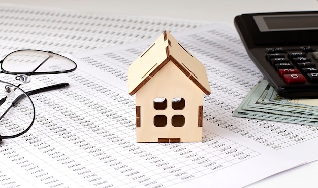 Petite maison en bois et calculatrice et dollars