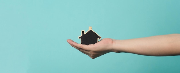 La petite maison en bois entre les mains représente des concepts tels que l'amour familial des soins à domicile