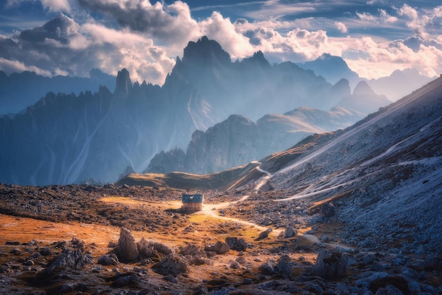 Petite maison dans la belle vallée de montagne pierres d'herbe orange ciel bleu avec des nuages au coucher du soleil en automne Paysage coloré avec des montagnes de construction Parc Tre Cime dans les Dolomites Italie Alpes en automne