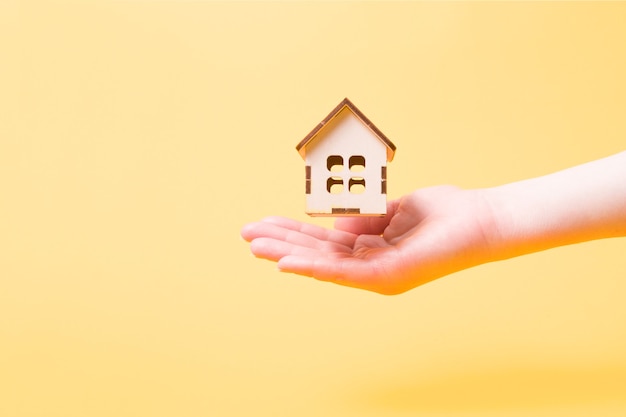 Petite maison de jouet en bois sur une main de femme