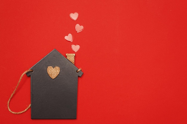 petite maison de jouet avec des coeurs rouges de tuyau sur fond rouge. Concept d'amour, de famille.