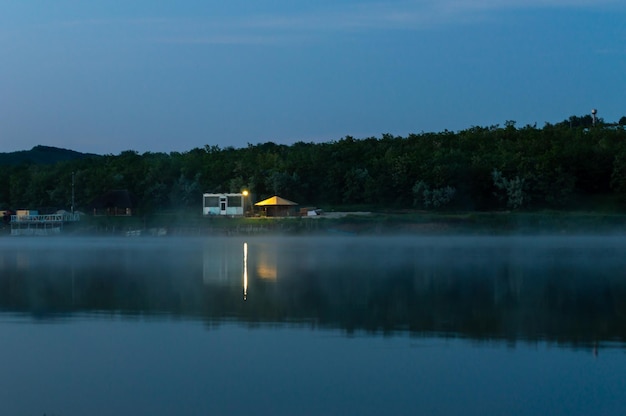 Petite maison avec une lanterne allumée tôt le matin sur le lac