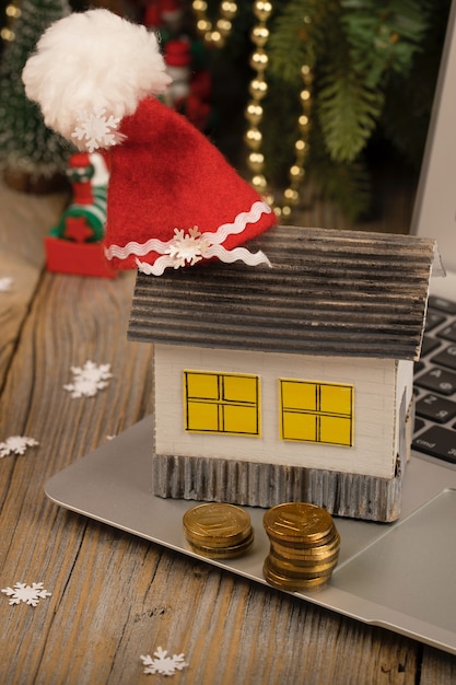 Petite maison en papier avec un chapeau de père Noël dessus placé sur un ordinateur portable en gros plan