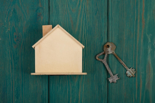 Petite maison vide et clé sur un bureau en bois bleu