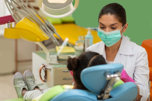 Petite patiente assise sur une chaise de dentiste