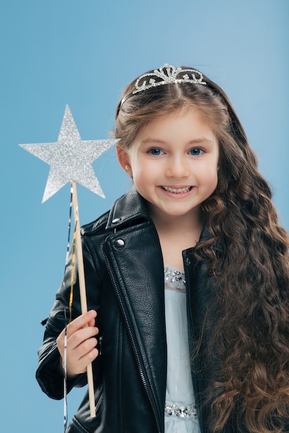 Petite petite fille satisfaite a de longs cheveux bouclés, vêtue d'une veste en cuir noire