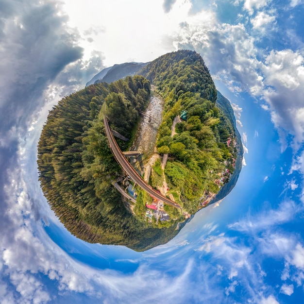 Photo petite planète avec un pont ferroviaire au-dessus d'une rivière de montagne