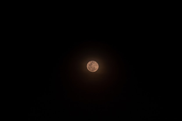 La petite pleine lune isolée sur noir