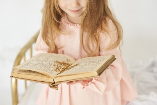 Petite princesse avec une baguette magique sur un lit dans un nuage sur fond blanc