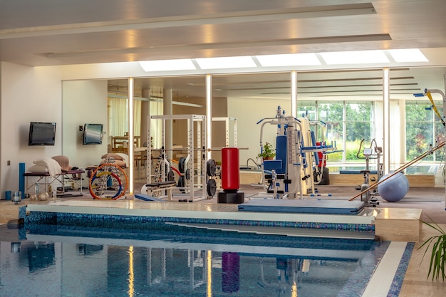 Petite salle de sport avec appareils de musculation et appareils de fitness dans la piscine intérieure de la maison