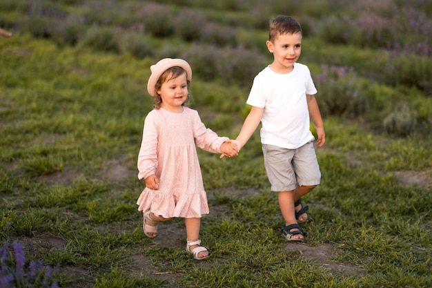 Photo petite soeur et frère se promènent dans un champ de lavande des enfants mignons marchent et s'embrassent dans la nature