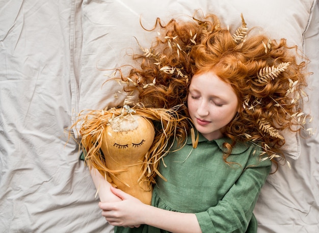 Une petite sorcière aux cheveux roux met sa fille citrouille au lit.