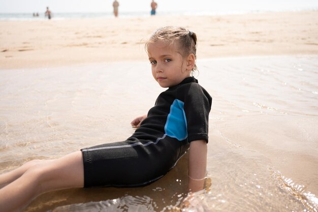 Photo une petite surfeuse en combinaison de plongée sur la plage de l'océan