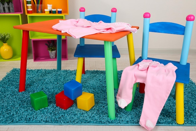 Petite table et chaises colorées avec des vêtements pour bébés