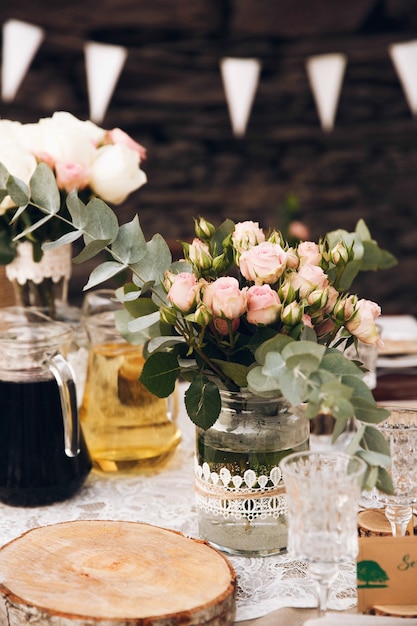 Petite table à dîner servie dans un style rustique et décorée de fleurs roses