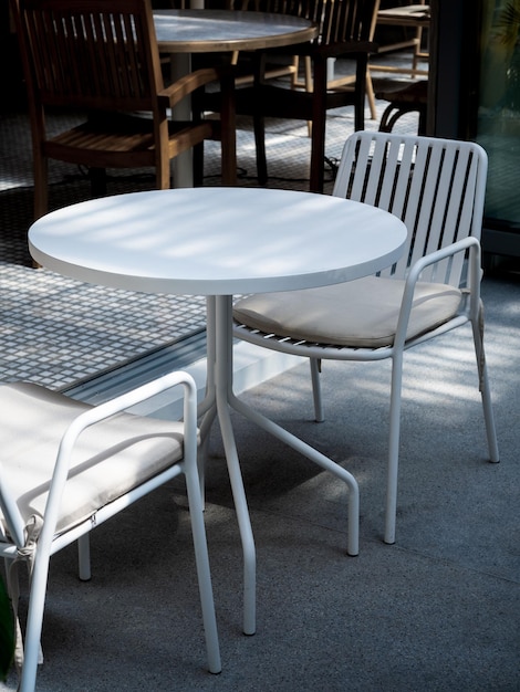 Petite table extérieure au restaurant ou au café de style vertical Table ronde blanche vide avec deux chaises vides devant le café