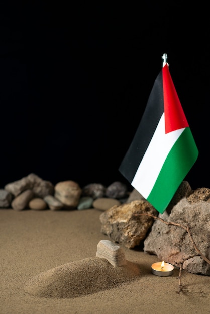 Petite tombe avec drapeau palestinien et pierres sur sable guerre funéraire mort Palestine