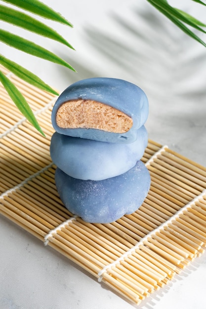 Une petite tour de gâteaux de riz sur une natte en bois Concept d'un mochi japonais traditionnel avec matcha bleu un tapis de maki sudare et des baguettes sur la table dessert asiatique mochi crème glacée équilibre alimentaire