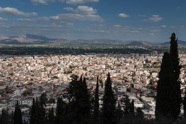 Petite ville grecque dans la vallée entourée de montagnes avec des silhouettes d'arbres en premier plan Argos Grèce