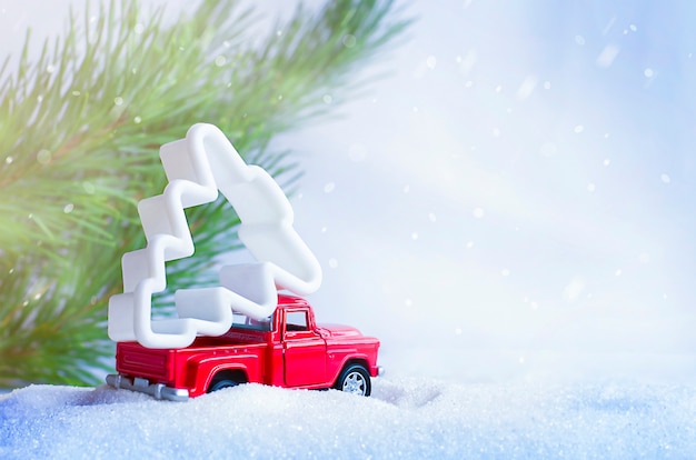 Petite voiture avec un arbre de Noël dans la forêt d'hiver