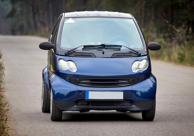 Petite voiture bleue roulant sur la route fond de voiture de ville moderne