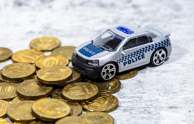 Une petite voiture avec l'inscription POLICE se dresse sur des pièces d'or Le concept de payer des amendes fiscales