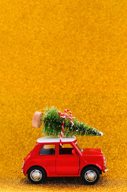 Petite voiture jouet rouge et arbre de Noël sur une étincelle d'or