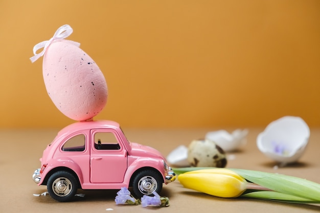 Petite voiture avec un œuf de Pâques sur le toit