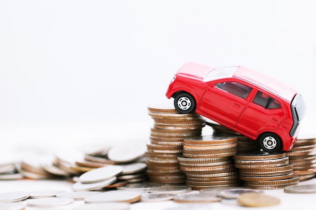 Petite voiture rouge sur beaucoup de pièces d'argent empilées. pour les prêts bancaires, les coûts de financement. assurance, achat de concept de financement automobile. acheter et payer par acomptes une voiture.