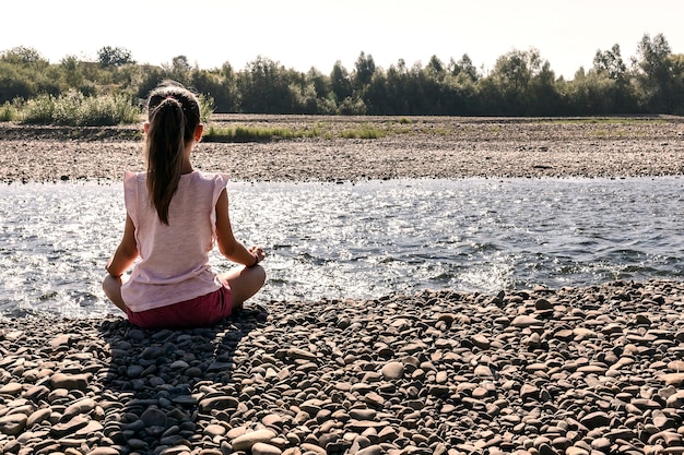 Photo petite yogagirl assise en position du lotus sur la rivière