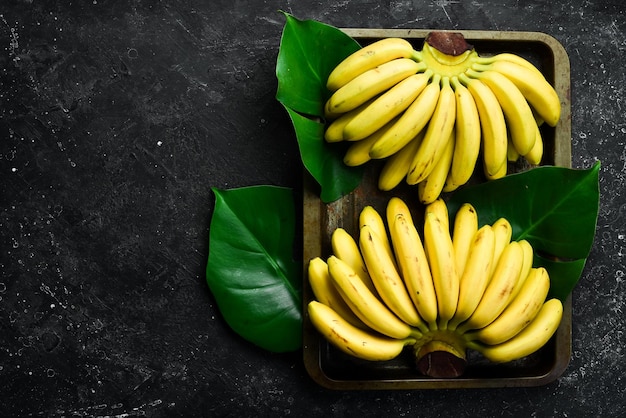 Petites bananes tropicales Ensemble de bananes Sur un fond de pierre noire Espace de copie gratuit