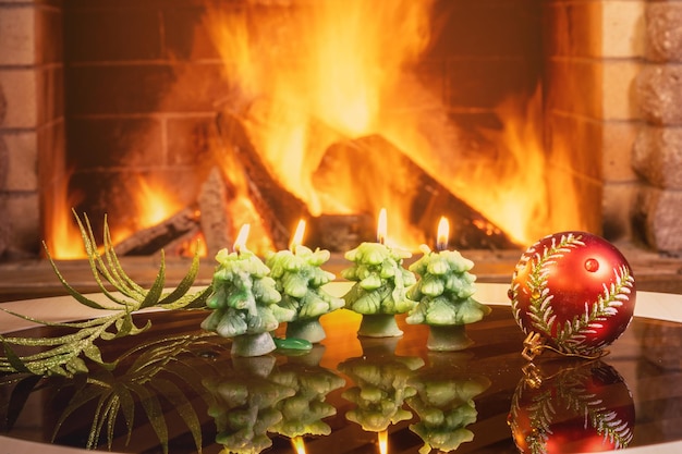 Petites bougies de noël en forme d'arbre du nouvel an devant une cheminée confortable