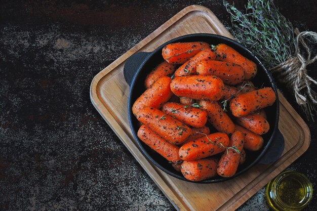 Petites carottes cuites aux herbes dans une poêle en fonte.