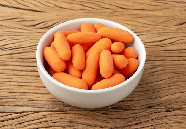 Petites carottes dans un bol sur une table en bois