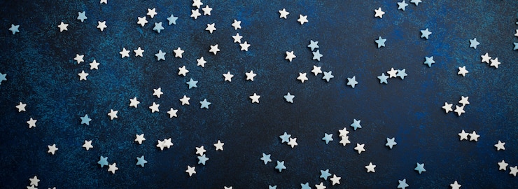 Photo petites étoiles blanches et bleues de bonbons sur un fond bleu foncé en béton ou en pierre. mise au point sélective. composition de noël. vue de dessus. espace de copie.