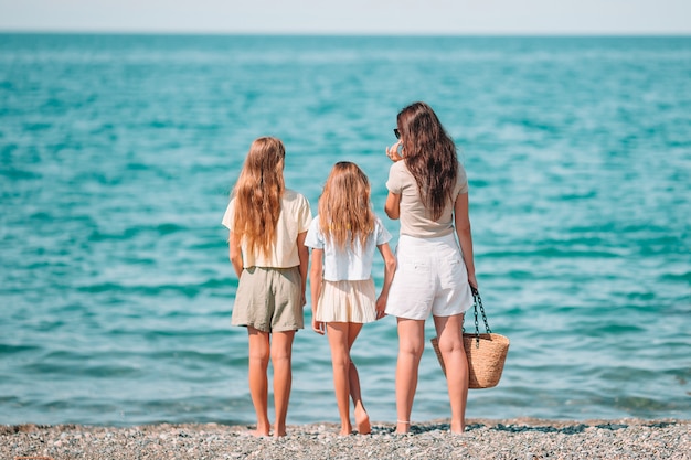 Petites filles adorables et jeune mère sur la plage blanche tropicale